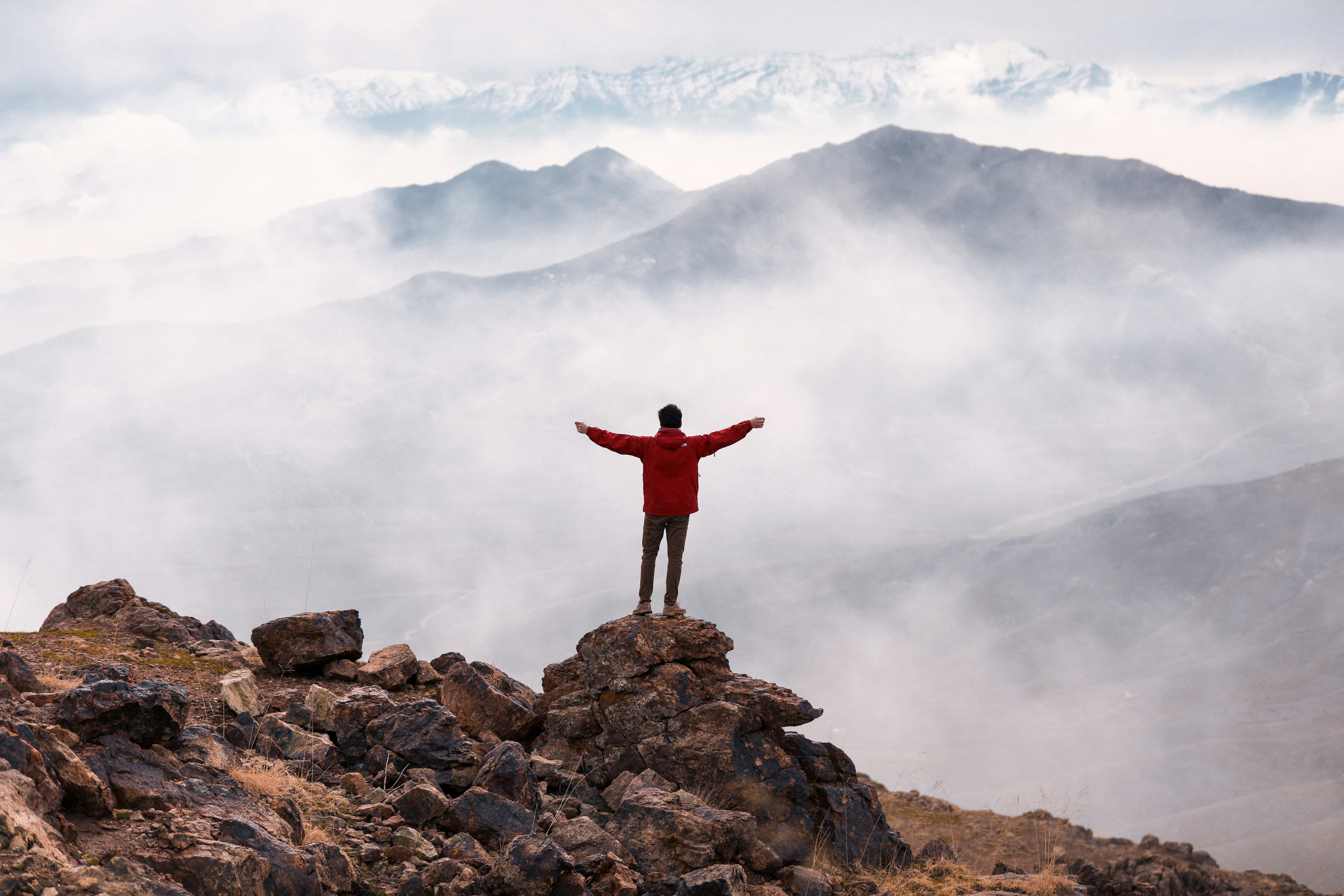 person in red long sleeve shirt standing on brown rock formation during daytime